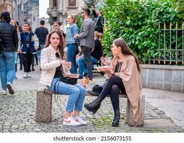 Bucharest, Romania - 04.08.2022:  Two beautiful young girls sitting on a bench in the old town center of Bucharest.