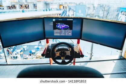 Bucharest, Romania - 2016: Triple screen setup with steering wheel and pedals installed on racing chair inside Bucharest Mall - Racing games for customers