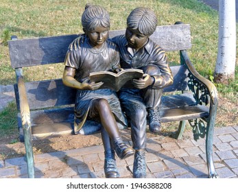 Bucharest, Romania - 8 27 2020: Metal characters representing two children reading a book sitting on a bench