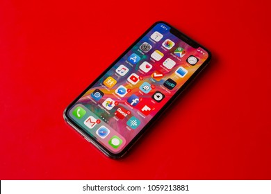 BUCHAREST, ROMANIA - APRIL 1, 2018: Photo Of An Iphone X Home Screen Full Of Icons And Apps On Red Background