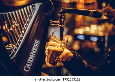 Bucharest, Romania - February 25, 2021: Illustrative editorial close up image of a bartender pouring a pint of Guinness beer in a pub.