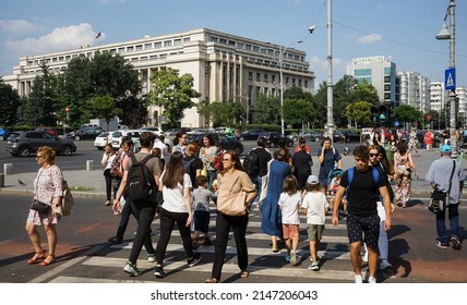 Bucharest, Romania - July 14, 2021: People cross the street near the Victoria Palace which houses the Romanian Government headquarters, in Bucharest.