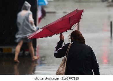 Bucharest, Romania - June 17, 2022: People Cross The Street During Heavy Rain.