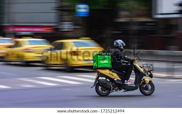 Bucharest, Romania - May 07, 2020: Uber Eats\
food delivery courier on a scooter in high speed. Restaurants are\
closed and only deliveries are allowed during the state of\
emergency due to\
coronavirus