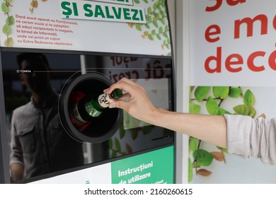Bucharest, Romania - May 25, 2022: Details with the hands of a man introducing glass bottles in a recycling equipment.
