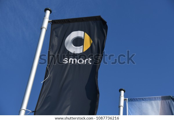 Buchholz, Lower Saxony\
/ Germany - April 22, 2018: Flags at the entrance of a Smart store\
in Buchholz, Germany - Smart is a German automotive marque and\
division of Daimler\
AG
