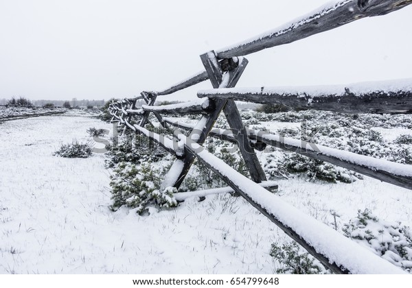 Buck\
and rail fence, also known as jackleg fence, in spring snow on\
historic site once ranchland in Grand Teton National Park, Wyoming,\
USA, for motifs of conservation and land\
management