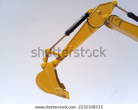 A bucket and arm of excavator miniature are captured in front of white background.