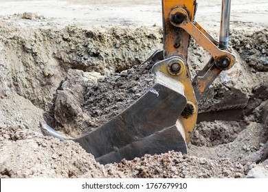 Bucket of a backhoe loader digging ground close up.