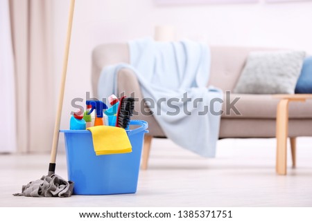 Bucket with cleaning supplies on floor indoors. Space for text