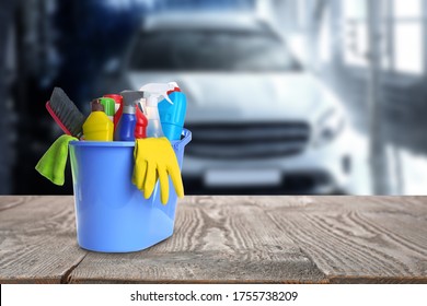 Bucket With Cleaning Supplies On Wooden Surface At Car Wash. Space For Text