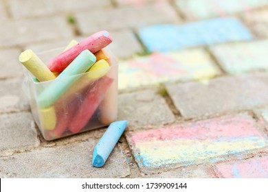 A Bucket Of Colorful Chalk On The Asphalt In Plastic Box. Drawing With Chalk On The Pavement. Multicolored Crayons For Drawing.