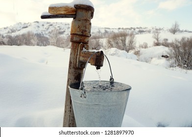A bucket filled with water from an iron column an a background of snow-covered hills!