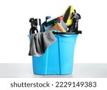 Bucket with many different car wash products on grey table against white background