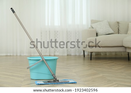 Bucket and mop on floor at home, space for text. Cleaning equipment