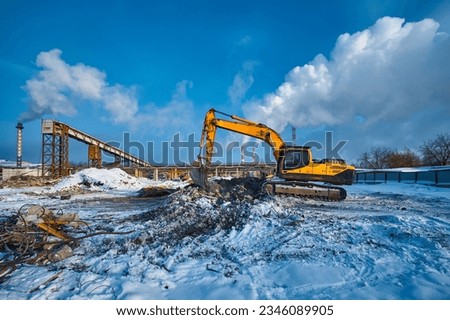 Bucket on excavator digs pit removing debris on winter day