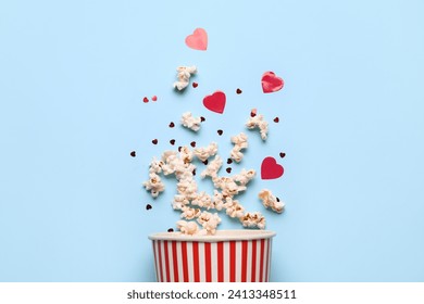 Bucket of popcorn with hearts decor on blue background. Valentine's Day celebration - Powered by Shutterstock