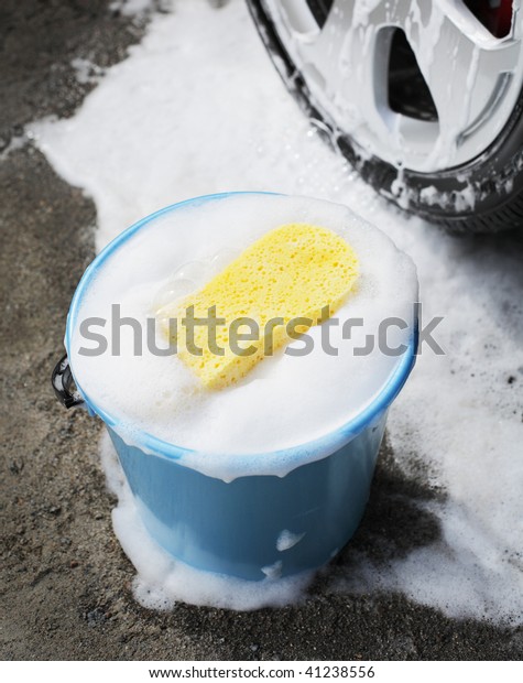 Bucket with\
soapy water, a sponge and a car\
wheel.