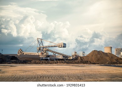 Máquina de rueda de cubo excavadora de gran tamaño de minería de superficie en la central eléctrica del Reino Unido que trabaja en montones de carbón a cielo abierto y montones de carbón en torres de refrigeración y cielo de nube dramáticas en el campo de carbón