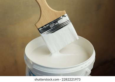 A bucket of white paint and a brush. Painting works in the premises. Tidying up the apartment. Repair of premises. The brush is dipped in white paint - Shutterstock ID 2282221973