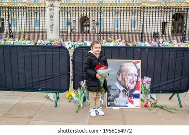 BUCKINGHAM PALACE, LONDON, ENGLAND- 10 April 2021: Child With Flowers Outside Buckingham Palace, Following The Death Of Prince Philip A Day Earlier