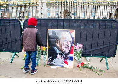 BUCKINGHAM PALACE, LONDON, ENGLAND- 10 April 2021: Child Placing Flowers Outside The Palace, Following The Death Of Prince Philip