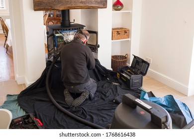 BUCKINGHAM, UK - April 20, 2020. Man Sweeping Wood Burning Stove And Chimney With A Flue Pipe In A Home, UK