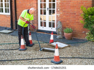 BUCKINGHAM, UK - August 07, 2015. Man Jetting Sewage Drain Outside House, Drain Cleaning Company Unblocking Main Sewage Pipe, UK