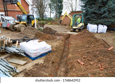 BUCKINGHAM, UK - December 02, 2016. Digger Driver, Digging A Trench For Drains On A UK Building Site