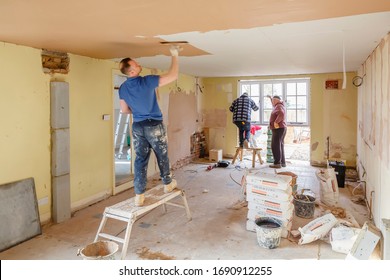 BUCKINGHAM, UK - March 14, 2016. Team of builders working on a home interior renovation with a plasterer plaster skimming a new ceiling