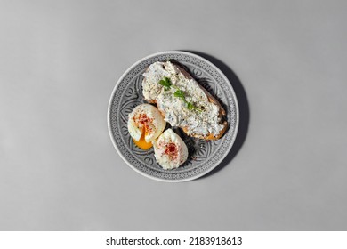 Buckwheat Bread Bruschetta With Philadelphia Cheese, Italian Herbs And Microgreen Pea Sprouts. Next To The Bruschetta Are Two Poached Eggs With The Yolk Flowing Out And Sprinkled With Ground Paprika. 