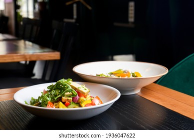 Buckwheat dumplings with fresh mushrooms and vegetable salad with cheese, fresh romatoes and cucumbers served in white plates on tbale in restaurant. Healthy eating concept.