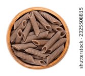 Buckwheat penne, gluten free whole grain pasta, in a wooden bowl. Dark brown noodles, made of pure buckwheat semolina, extruded into cylinder-shaped pieces, their ends cut at an angle, then dried.