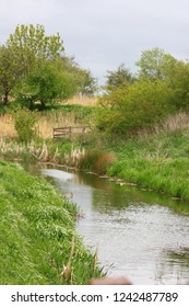 Bucolic View Of A Serene Stream Flowing Across The Countryside At The Flag Fen Archaeology Park In Peterborough, England.