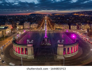 Budapest, Hungary - Aerial drone view of the famous Heroes' Square (Hosok tere) lit up in unique purple and pink color by night with a colorful sunset 