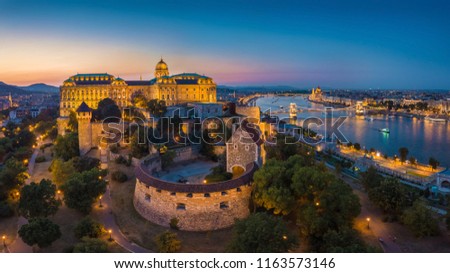 Budapest, Hungary - Aerial panoramic skyline view of beautiful illuminated Buda Castle Royal Palace with Szechenyi Chain Bridge, Hungarian Parliament at blue hour
