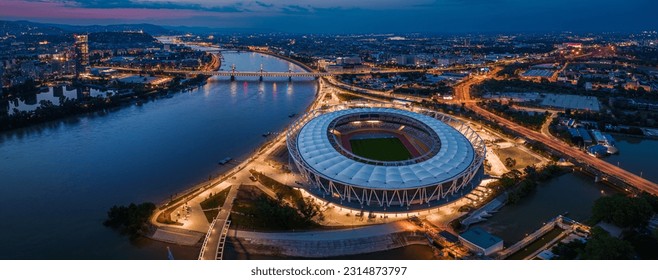 Budapest, Hungary - Aerial panoramic view of Budapest at dusk, including illuminated National Athletics Centre, Rakoczi bridge, Puskas Arena and MOL Campus skyscraper building at background at sunset