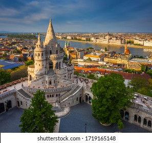 Budapest, Hungary - Aerial View Of The Famous Fisherman's Bastion At Sunset With Parliament Building At Background. Warm Sunlight, Blue Sky, No People On A Sunny Spring Afternoon