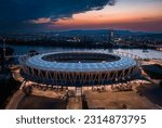 Budapest, Hungary - Aerial view of the illuminated National Athletics Centre at Danube riverbank with Rakoczi bridge, MOL Campus skyscraper building and colorful sunset sky at backgorund