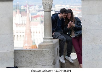 Budapest, Hungary - April 26, 2022: Young Couple Enjoying Photos Taken On Their Mobile Device At A Scenic View Over Danube River