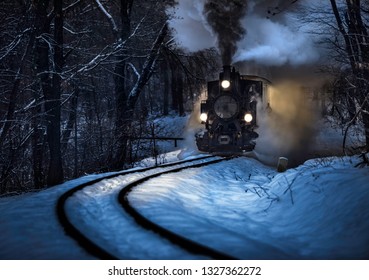Budapest, Hungary - Beautiful winter forest scene with snow and old steam locomotive on the track in the Hungarian woods of Huvosvolgy at night