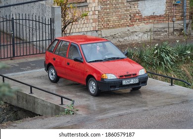 BUDAPEST, HUNGARY - CIRCA 2019: Old Suzuki Swift Parked On A Driveway, Rainy Weather. Popular Small Car Made In The Beginning Of 90s. September 1992 Production In Esztergom, Hungary Started