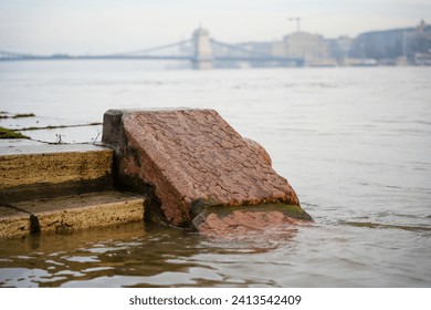 Budapest, Hungary - December 30, 2023: Flooded stone staircase on the Danube river bank. Chain bridge on the background.