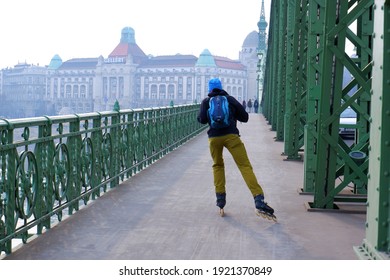 Budapest, Hungary - February, 18, 2021: Roller Skater Man On Freedom Bridge In Foggy City