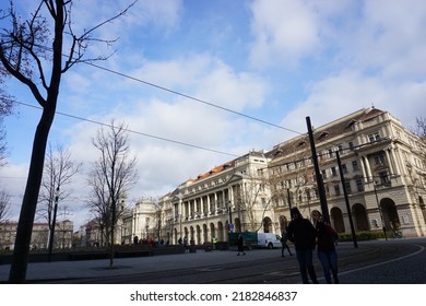 Budapest, Hungary - February 5th 2019 : View Around Hungarian Parliament Building, Scenery Of Ministry Of Agriculture Building, Deciduous Trees, People, Cable Tram, Road, Blue Sky And White Cloud