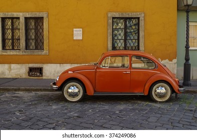 Budapest, Hungary - July 9, 2015: Orange Retro Economy Car - Volkswagen Beetle Parked On The Old Street Of Budapest. Side View