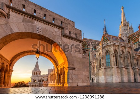 Budapest, Hungary - North gate of the Fisherman's Bastion (Halaszbastya) with the beautiful Matthias Church at golden sunrise and clear blue sky