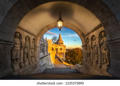 Budapest, Hungary - South Entrance Of The Famous Fisherman's Bastion (Halaszbastya) Of Buda District At Sunrise With Lamp, Golden Morning Lights, Autumn Foliage And Beautiful Sky