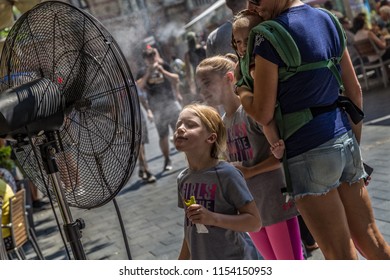 BUDAPEST,HUNGARY-AUGUST 09,2018 :Unidentified  People Alleviate The Summer Heat Wave In Front Of The Water Spraying Fan At The Street Of Downtown. 