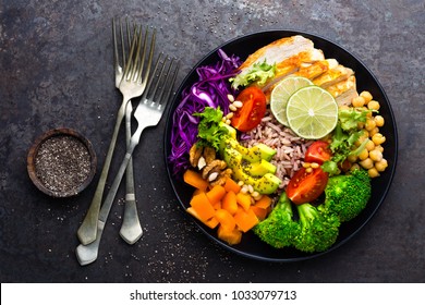 Buddha Schüssel mit Hühnerfilet, brauner Reis, Avocado, Pfeffer, Tomate, Broccoli, roter Kohl, Huhn, Salat mit frischem Salat, Kiefernnüsse und Walnüsse. Gesunde, ausgewogene Ernährung. Draufsicht